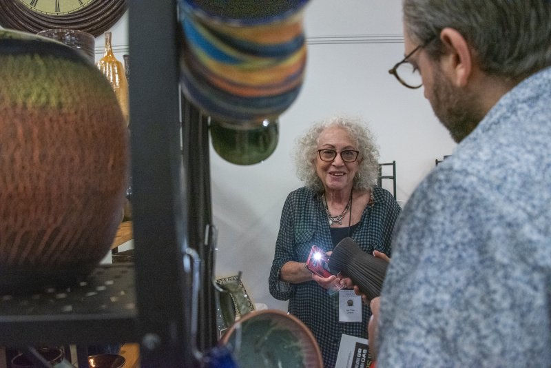 Milton artist Ava Thaw uses a flashlight to show how different finishes react to light in her ceramic vessels.
